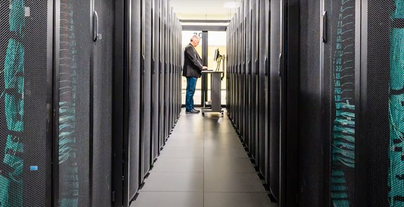 A man stands in between the rows of a super computer