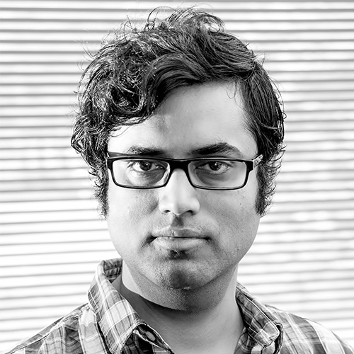 Headshot of Princeton Plasma Physics researcher Ammar Hakim. His headshot is in black and white. He smiles and wears a flannel button up. He stands in front of an abstract background.