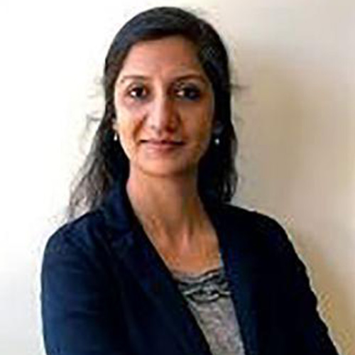 Headshot of Argonne researcher Rachana Ananthakrishnan. She wears a blue and white blouse with blue cardigan. She stands in front of a white background.