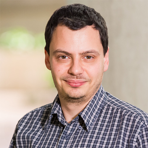 Headshot of Argonne researcher Bogdan Nicolae. He smiles and wears a blue plaid button up. He stands in front of a blurred background.