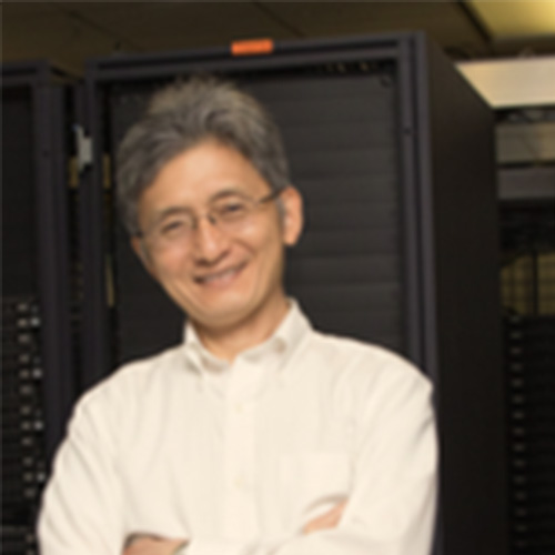 Headshot of SLAC researcher Chin Fang. He smiles and wears a white button up. He stands in front of a computing machine. 