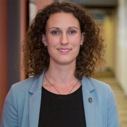 Headshot of Lawrence Berkeley researcher Deborah Bard. She smiles and wears a black blouse with light blue blazer. She stands in an office hallway. 