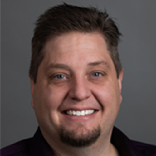 Photo of National Energy Technology researcher Dirk VanEssendelft. He smiles and stands against a dark grey backdrop.