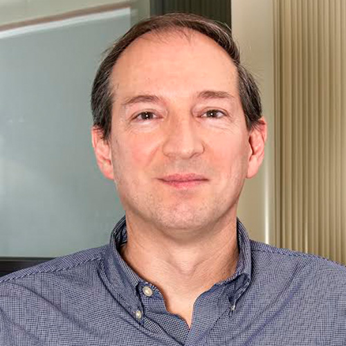 Headshot of Princeton Plasma Physics researcher Stephane Ethier. He smiles and wears a dark blue button up. He stands in an office.