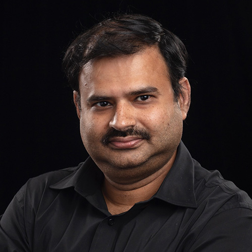 Headshot of Oak Ridge researcher Ramakrishnan Kannan. He smiles and wears a black button up. He stands in front of a black backdrop.