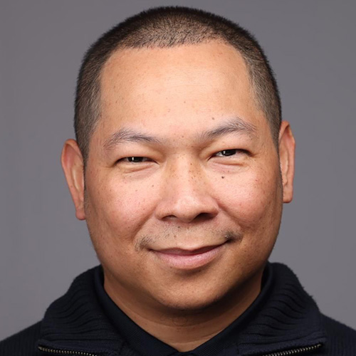 Headshot of Ames researcher Sarom S. Leang. He smiles and wears a black pull over with black undershirt. He stands in front of a light grey backdrop.