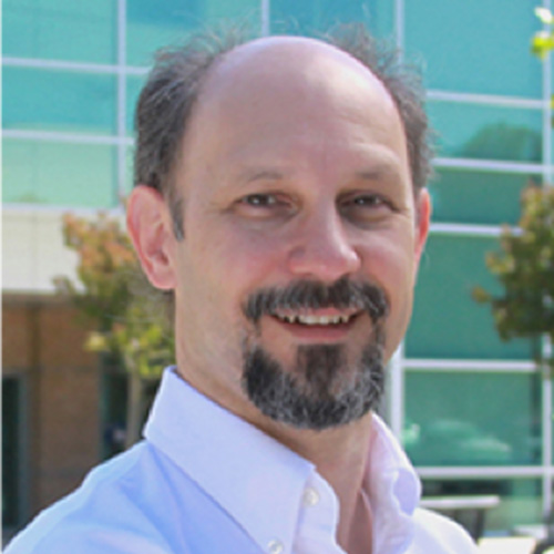 Headshot of Lawrence Livermore researcher Fred Streitz He smiles, wears a light colored button up and stands against a nature scene. 